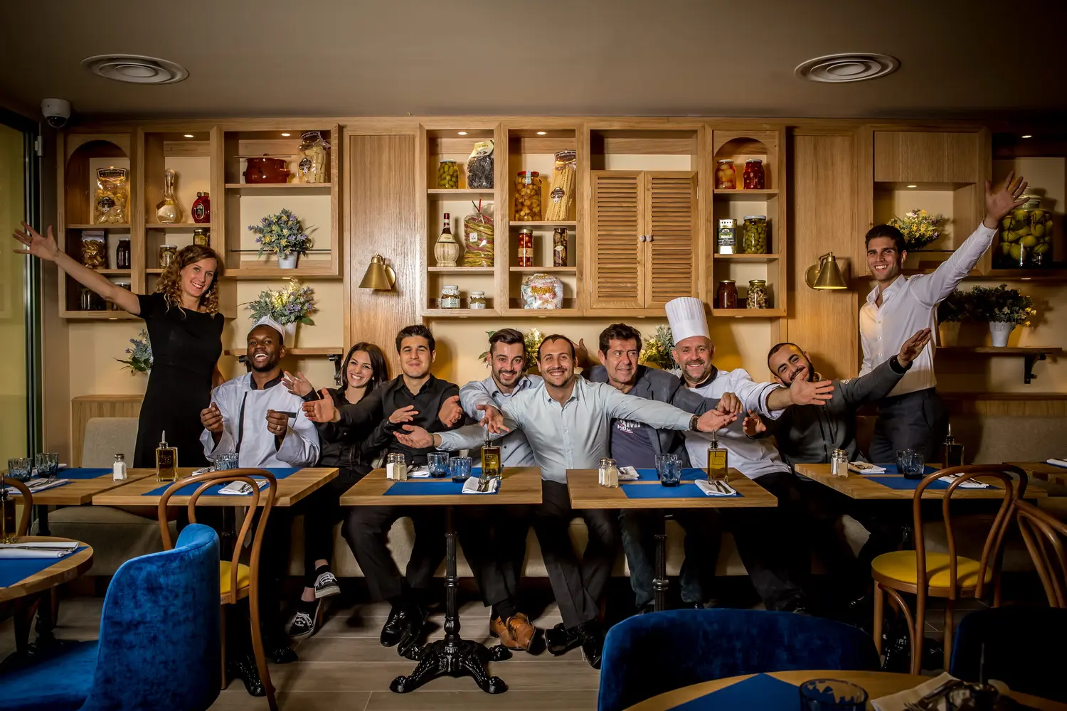 Il team del Casa Leya a tavola davanti alla parete di alimentari italiani