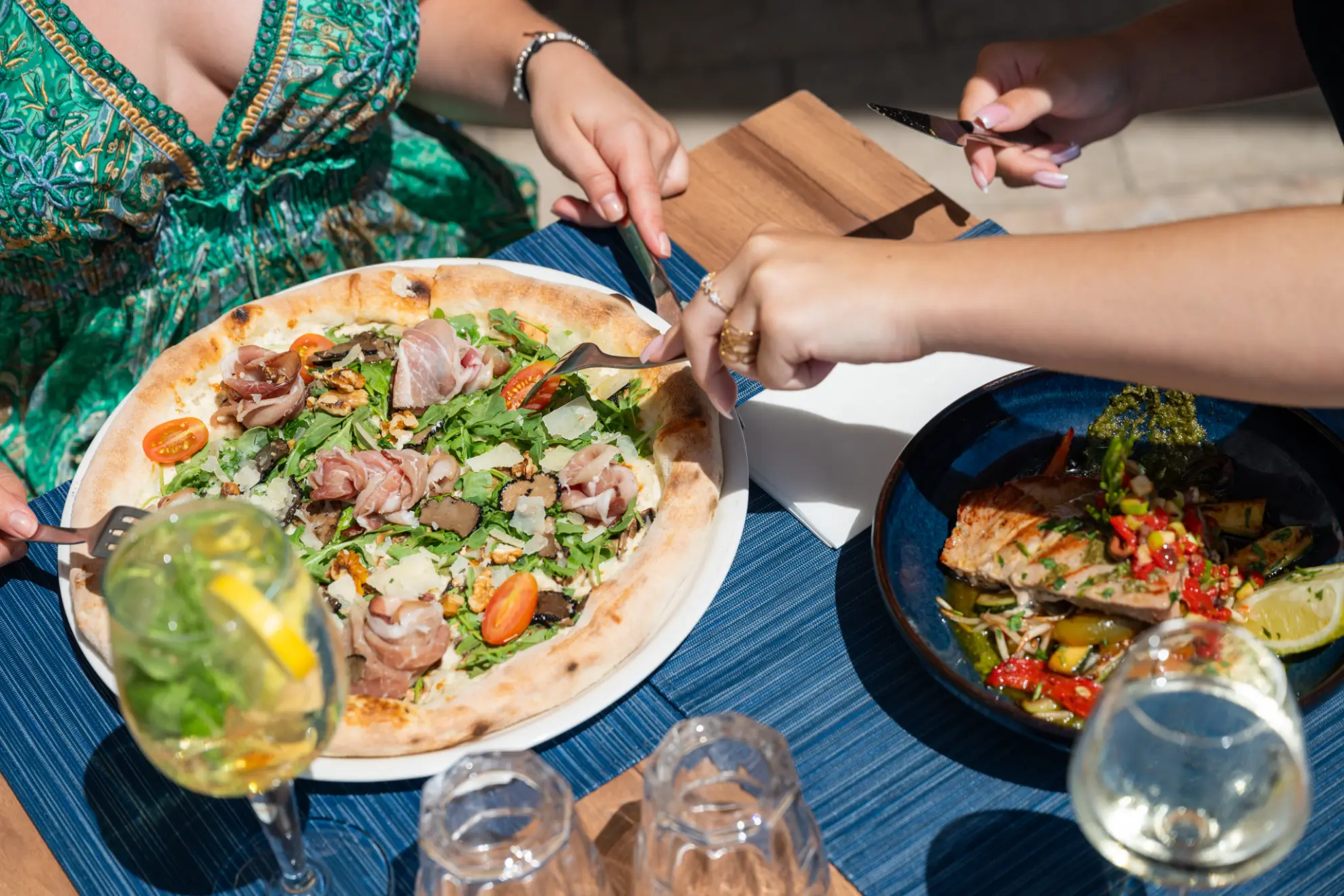 Pizza au jambon de Parme partagée en terrasse, avec un pavé de thon
