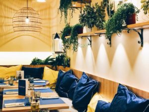 Image représentant le premier étage du restaurant qui est un lieu avec une ambiance chaleureuse, il est décoré comme le reste du restaurant avec les couleurs provençales, le jaune et le bleu. Il y a des banquettes et des chaises confortables pour garantir une bonne expérience.